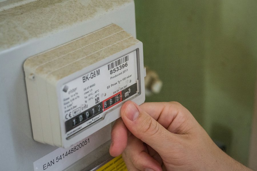 Käsi sähkönkulutusta mittaavan energiamittarin vieressä